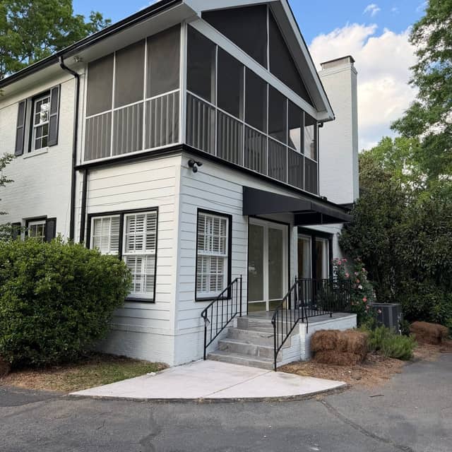 Side elevation of a pale grey home with a two-storey screened porch and freshly painted white trim