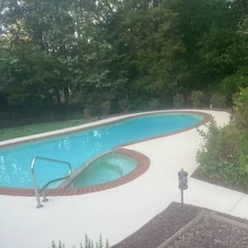 Swimming pool surrounded by clean, bright concrete decking with brick coping