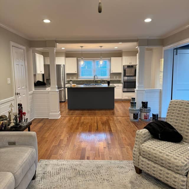 Open-plan living room looking through to a white kitchen, with painted trim and column detailing