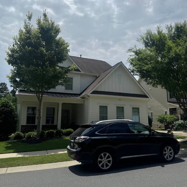 Cream-painted home with a dark car parked on the drive and freshly finished white trim