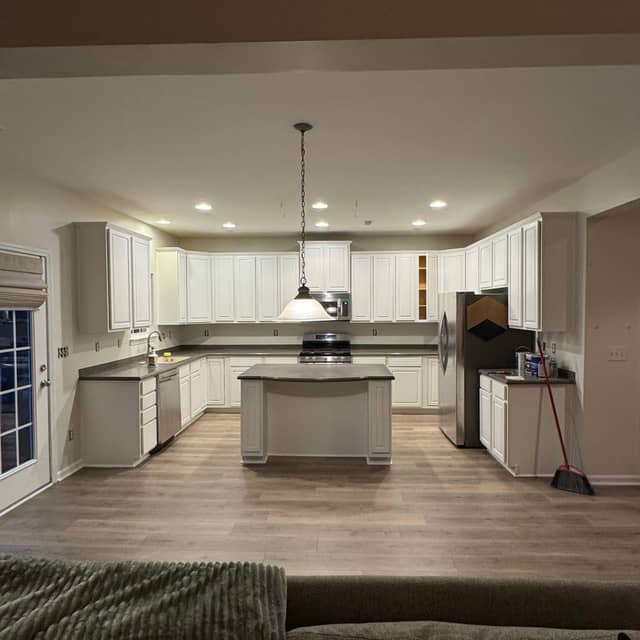 White painted kitchen cabinets and island viewed from the adjoining living space